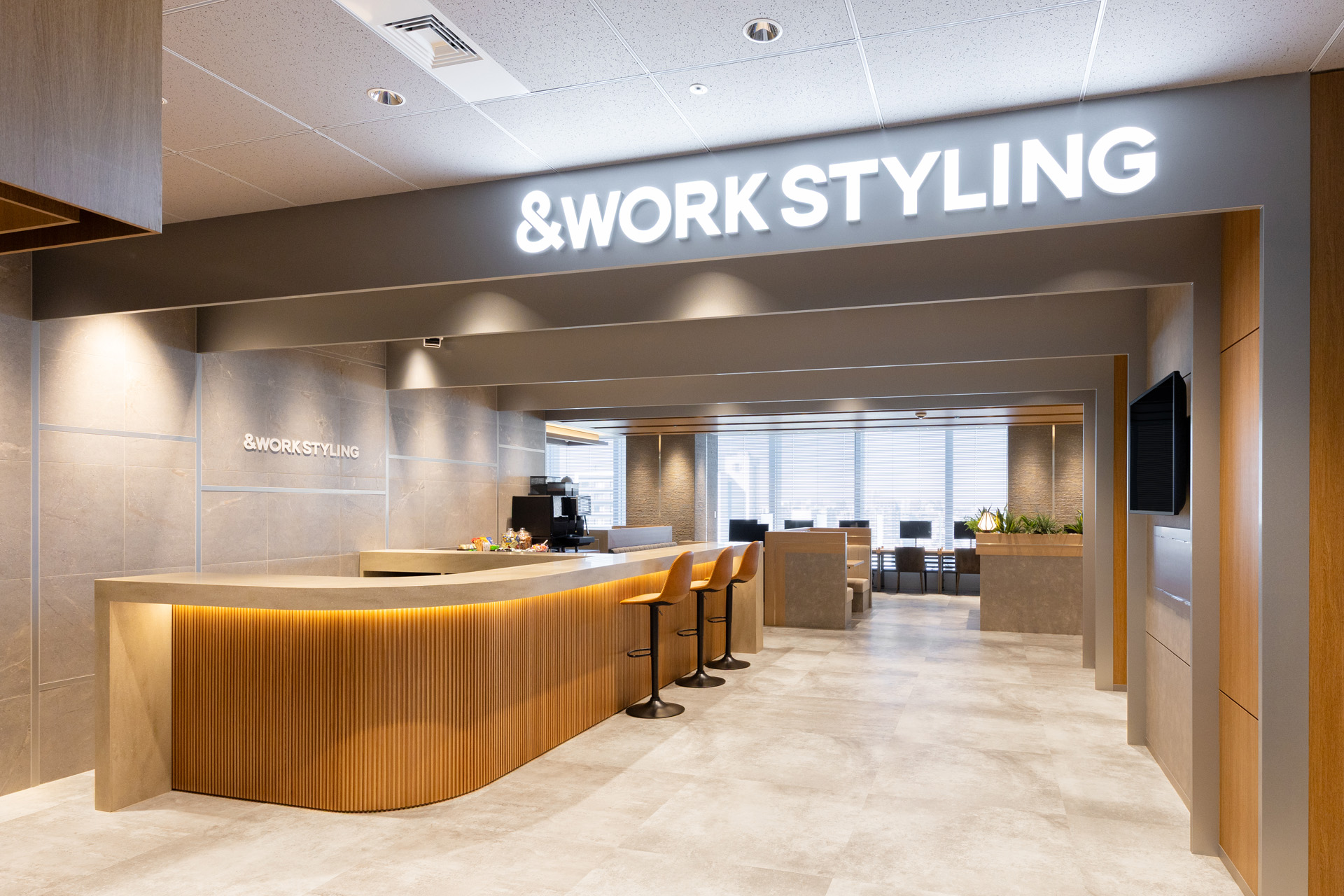 東京都千代田区富士見の飯田橋グラン・ブルーム内、飯田橋駅近くのビルディングにあるワークスタイリング飯田橋の受付とオープンスペース。jr西口から徒歩1分、東京メトロ東西線・有楽町線・南北線、都営大江戸線飯田橋駅の出口・出入口から徒歩2分でアクセスしやすい、落ち着いた空間