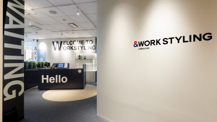 ワークスタイリング神保町のエントランスの画像。Helloと表示された受付カウンターとWORK STYLING JIMBOCHOのサインが見える、明るくモダンな周辺拠点