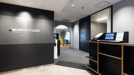ワークスタイリング御茶ノ水のエントランスの画像。受付カウンターとブランドサイン、 その先にオープンスペースや会議室を思わせる空間が見える、飯田橋駅周辺拠点とあわせて利用しやすい周辺拠点